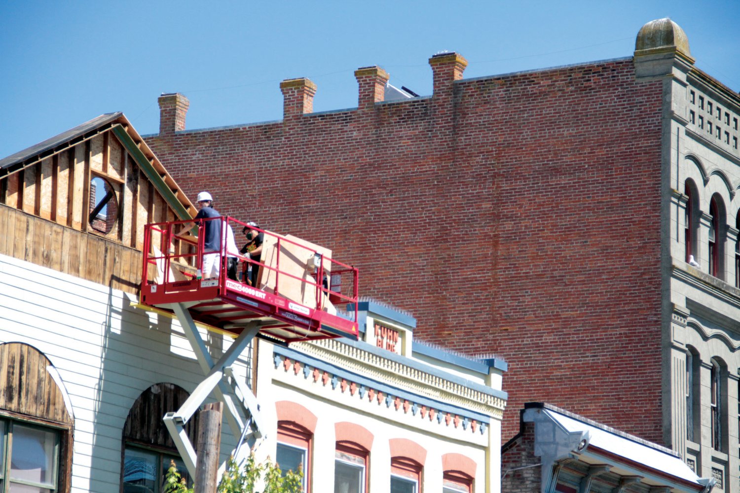A crew from G. Little Construction removes siding from the top of the building at 936 Water Street in Port Townsend.